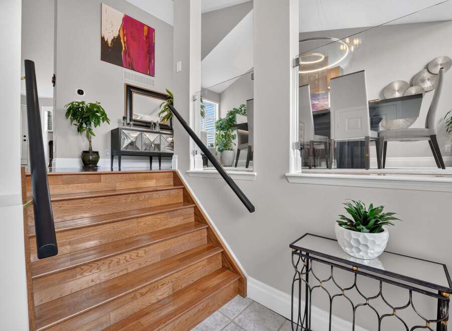 Step into this elegant home featuring a grand wooden staircase leading to the upper level.