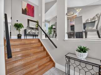 Step into this elegant home featuring a grand wooden staircase leading to the upper level.