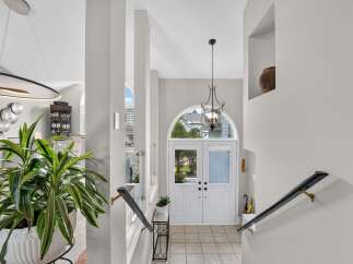 Step into a grand entryway featuring elegant double doors with arched transoms, flooding the space with natural light.