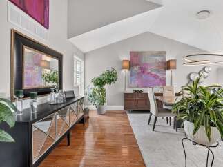 This elegant dining room features a vaulted ceiling and a large abstract painting that adds a pop of color.