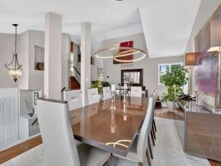 Experience elegant dining in this sophisticated space, featuring a sleek, high-gloss dining table surrounded by plush white chairs.