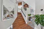 This stunning entryway features a grand wooden staircase leading to the upper level, complemented by a large framed artwork on the left wall.