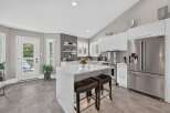Experience modern living in this stunning kitchen featuring sleek white cabinetry, a spacious quartz island with seating, and stainless steel appliances.