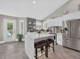 Experience modern living in this stunning kitchen featuring sleek white cabinetry, a spacious quartz island with seating, and stainless steel appliances.