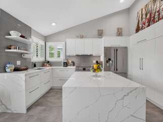 Experience modern luxury in this stunning kitchen, featuring sleek white cabinetry and a breathtaking marble island.