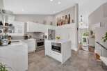 Experience modern luxury in this stunning kitchen featuring sleek white cabinetry, elegant marble countertops, and a central island with a built-in microwave.