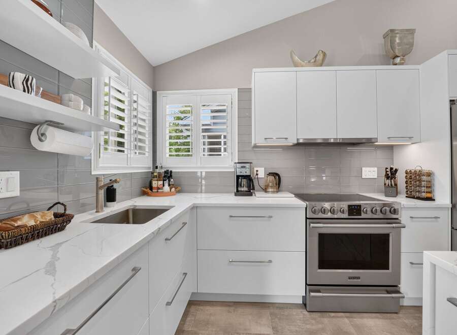 Experience modern elegance in this stunning kitchen, featuring sleek white cabinetry and gleaming quartz countertops.