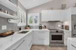 Experience modern elegance in this stunning kitchen, featuring sleek white cabinetry and gleaming quartz countertops.