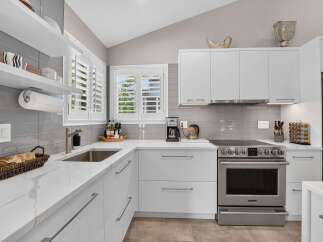 Experience modern elegance in this stunning kitchen, featuring sleek white cabinetry and gleaming quartz countertops.