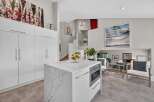 Experience modern living in this stunning kitchen featuring a sleek white island with a marble countertop and integrated microwave.
