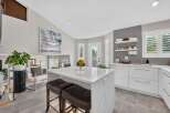 Experience modern luxury in this stunning kitchen, featuring a sleek white island with marble countertops and comfortable bar stools.
