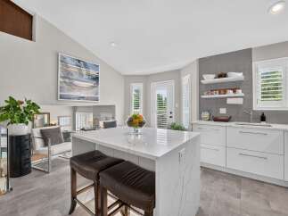 Experience modern luxury in this stunning kitchen, featuring a sleek white island with marble countertops and comfortable bar stools.