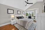 Experience luxury in this master bedroom, featuring a vaulted ceiling with a modern ceiling fan and ample natural light from the large windows.