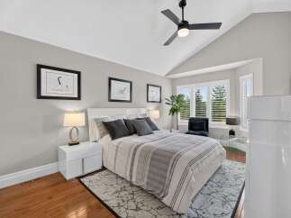 Experience luxury in this master bedroom, featuring a vaulted ceiling with a modern ceiling fan and ample natural light from the large windows.