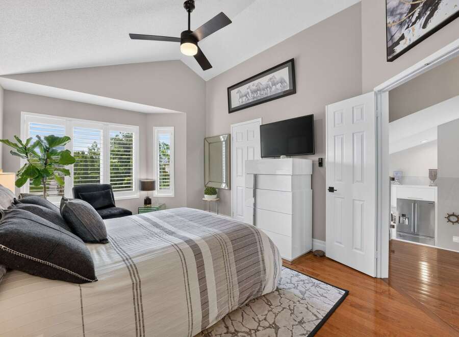 Experience luxurious comfort in this master bedroom, featuring a plush king-sized bed adorned with elegant grey and white striped bedding and decorative pillows.