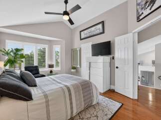 Experience luxurious comfort in this master bedroom, featuring a plush king-sized bed adorned with elegant grey and white striped bedding and decorative pillows.
