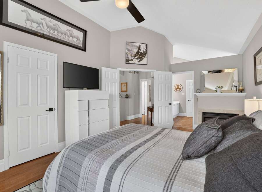 Experience luxury and comfort in this stunning master bedroom, featuring a vaulted ceiling and a cozy fireplace.