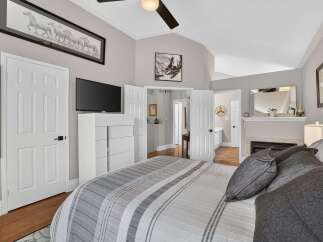 Experience luxury and comfort in this stunning master bedroom, featuring a vaulted ceiling and a cozy fireplace.
