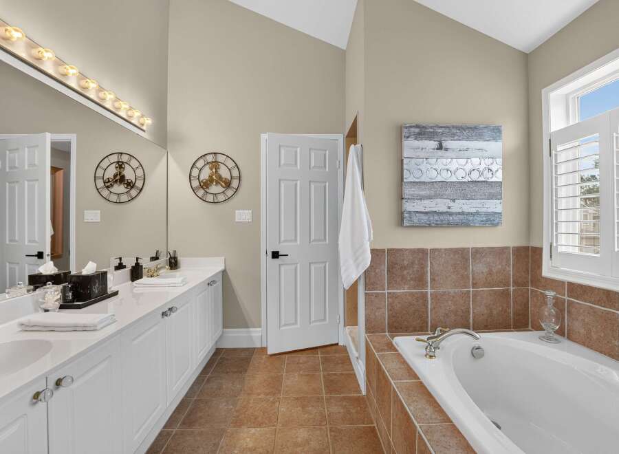 This spacious bathroom features a double vanity with ample counter space and storage, complemented by a large mirror and vanity lighting.