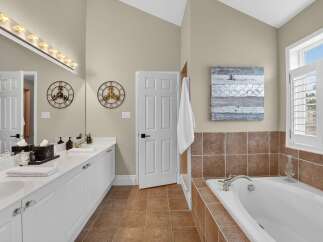 This spacious bathroom features a double vanity with ample counter space and storage, complemented by a large mirror and vanity lighting.
