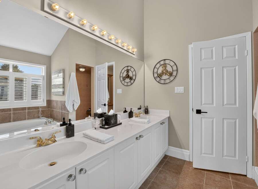 Experience luxury in this stunning bathroom featuring a spacious double vanity with elegant gold fixtures and ample counter space.