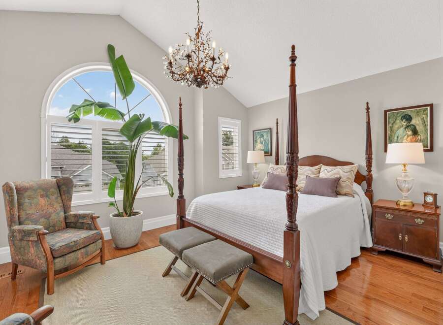Experience luxury and comfort in this stunning master bedroom, featuring a grand four-poster bed and a beautiful arched window that floods the space with natural light.