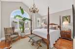 Experience luxury and comfort in this stunning master bedroom, featuring a grand four-poster bed and a beautiful arched window that floods the space with natural light.