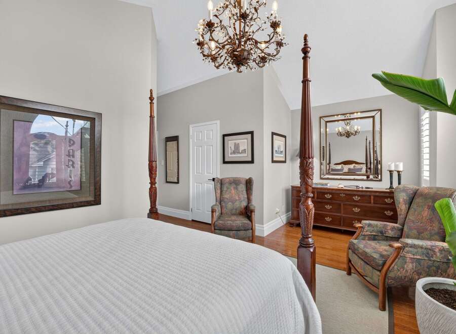 Experience luxury in this master suite featuring a grand four-poster bed and a stunning crystal chandelier.