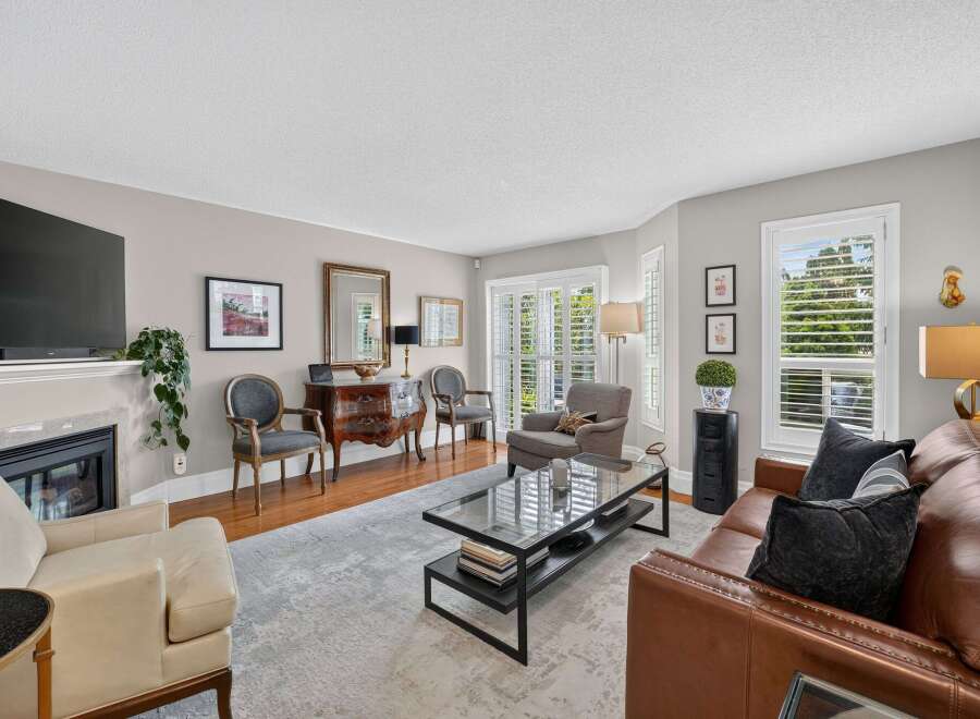 Step into this inviting living room, featuring a plush brown leather sofa and a comfortable cream armchair perfect for relaxation.