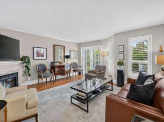 Step into this inviting living room, featuring a plush brown leather sofa and a comfortable cream armchair perfect for relaxation.