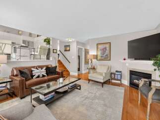 Step into this inviting living room, featuring a luxurious brown leather sofa adorned with Union Jack pillows, perfect for cozy evenings.