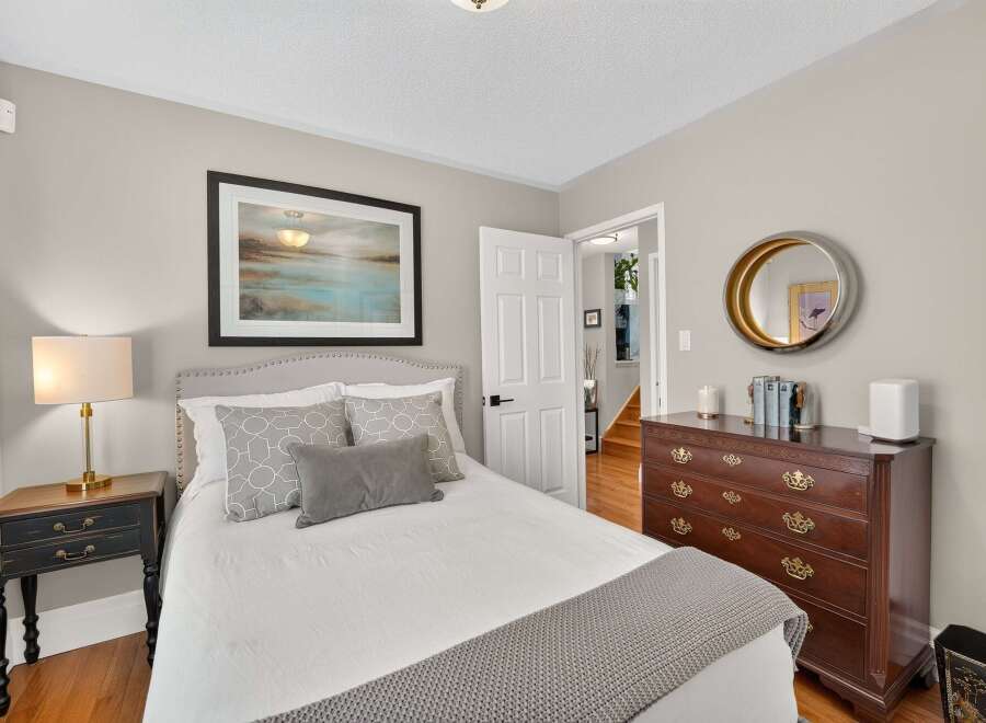 Discover this charming bedroom featuring a comfortable bed with decorative pillows and a cozy knit throw.