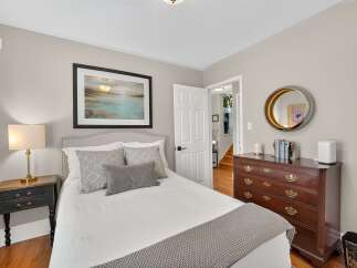 Discover this charming bedroom featuring a comfortable bed with decorative pillows and a cozy knit throw.