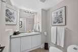 This elegant bathroom features a spacious vanity with a granite countertop and a gold-accented faucet, complemented by a large mirror with a vanity light fixture.