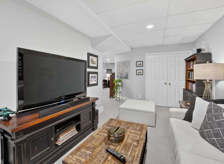 This inviting living space features a large flat-screen TV mounted above a dark wood entertainment center, perfect for movie nights.