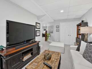This inviting living space features a large flat-screen TV mounted above a dark wood entertainment center, perfect for movie nights.