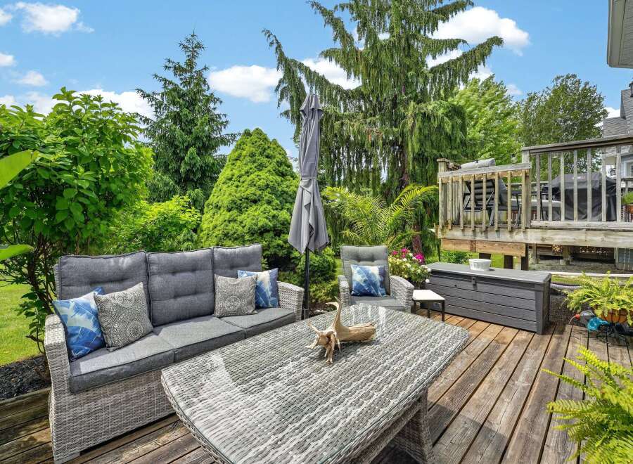 Enjoy outdoor living at its finest on this spacious deck, featuring comfortable wicker furniture and a dining table perfect for al fresco meals.