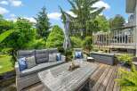 Enjoy outdoor living at its finest on this spacious deck, featuring comfortable wicker furniture and a dining table perfect for al fresco meals.