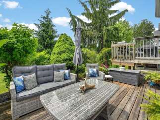 Enjoy outdoor living at its finest on this spacious deck, featuring comfortable wicker furniture and a dining table perfect for al fresco meals.
