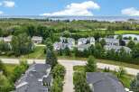 Discover this stunning aerial view of a serene residential community nestled amidst lush greenery and overlooking a tranquil body of water.