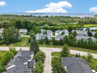 Discover this stunning aerial view of a serene residential community nestled amidst lush greenery and overlooking a tranquil body of water.
