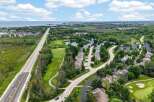 Experience luxury living with this stunning aerial view of a residential community nestled beside a golf course and overlooking a serene body of water.