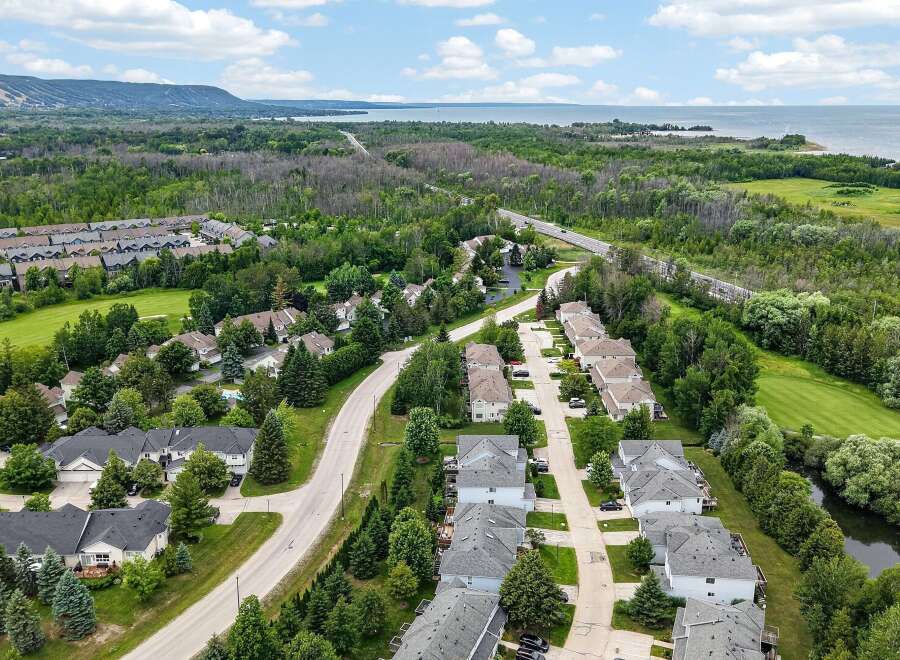 Discover this picturesque suburban neighborhood featuring a collection of modern townhouses nestled amidst lush greenery and mature trees.