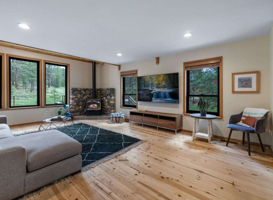 Experience cozy living in this inviting living room, featuring a striking stone fireplace with a wood-burning stove as the centerpiece.