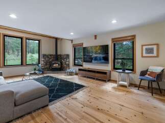 Experience cozy living in this inviting living room, featuring a striking stone fireplace with a wood-burning stove as the centerpiece.
