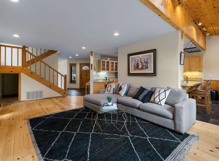 Step into this inviting living space featuring a comfortable sectional sofa adorned with decorative pillows, perfectly positioned on a stylish dark rug.