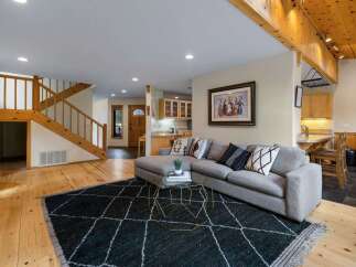 Step into this inviting living space featuring a comfortable sectional sofa adorned with decorative pillows, perfectly positioned on a stylish dark rug.