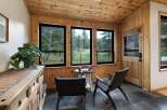 Enjoy the serene forest views from this charming sunroom, featuring abundant natural light and warm wood paneling throughout.