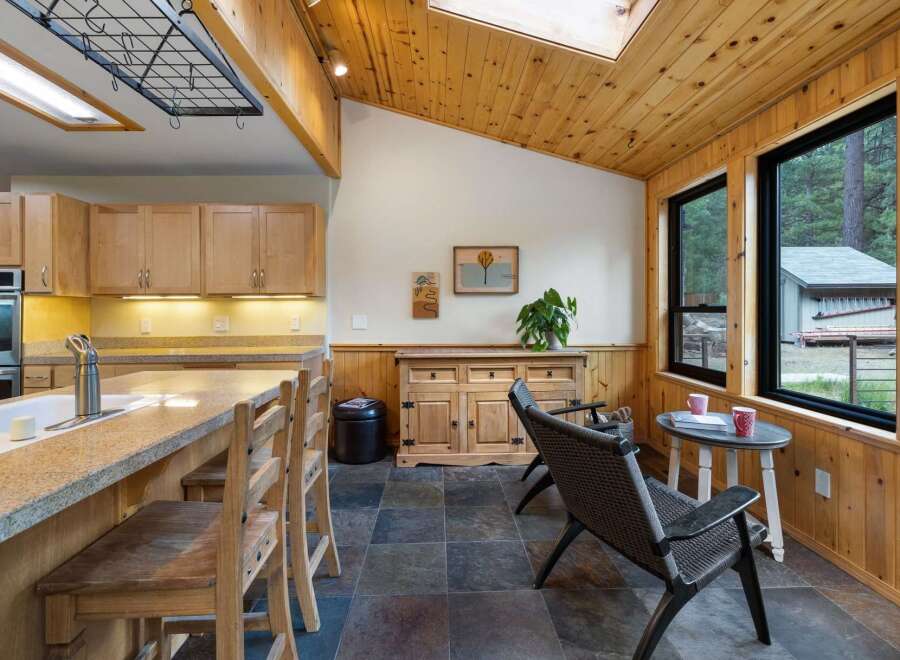 This charming kitchen and dining area features warm wood accents throughout, including vaulted wood-paneled ceilings and wainscoting.