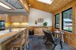 This charming kitchen and dining area features warm wood accents throughout, including vaulted wood-paneled ceilings and wainscoting.